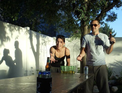 The couple plays a game of beer pong while their shadows play something else.