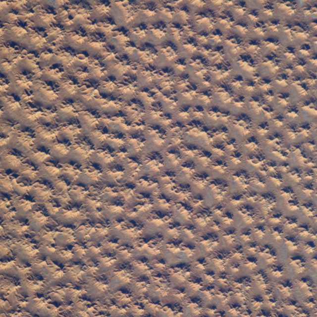The indentations look like footprints in the sand or artificial leather.