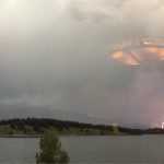 Photo of a UFO in a storm with lightning in the background.